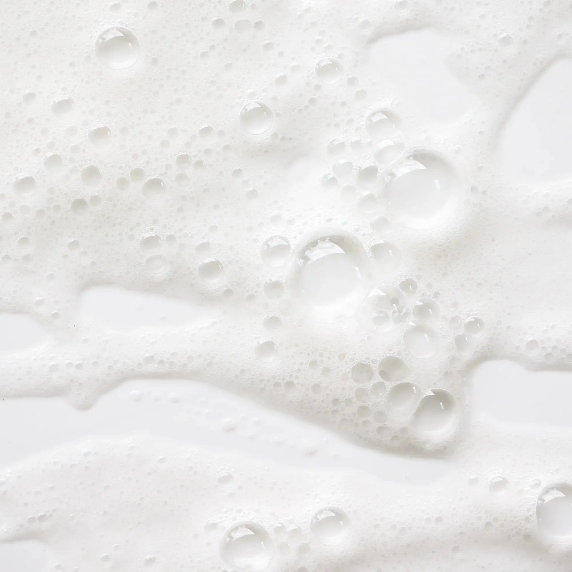 Zoom sur la mousse fine et aérienne du savon liquide Fleur d'Oranger, avec des bulles blanches sur fond clair
