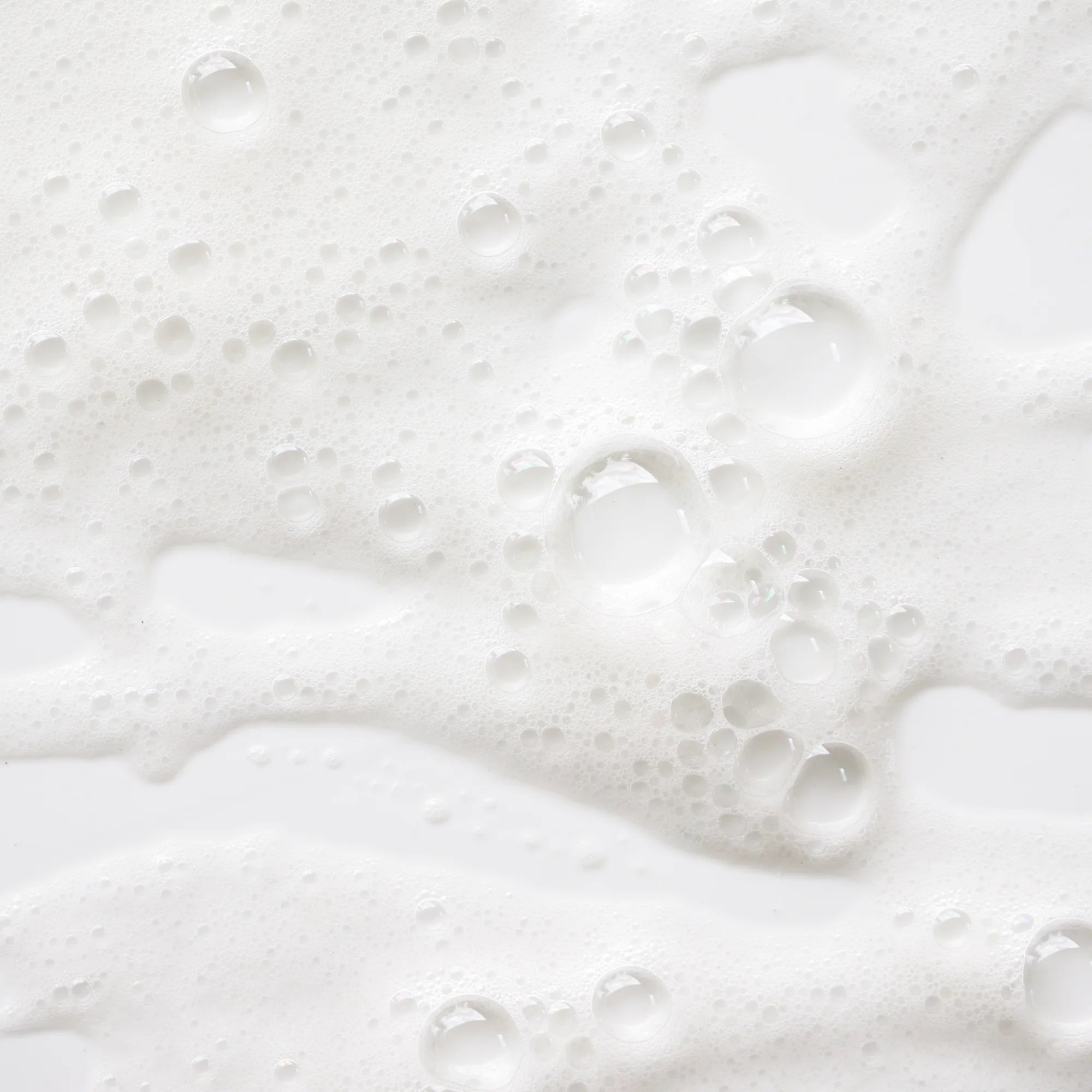 Zoom sur la mousse fine et aérienne du savon liquide Fleur d'Oranger, avec des bulles blanches sur fond clair